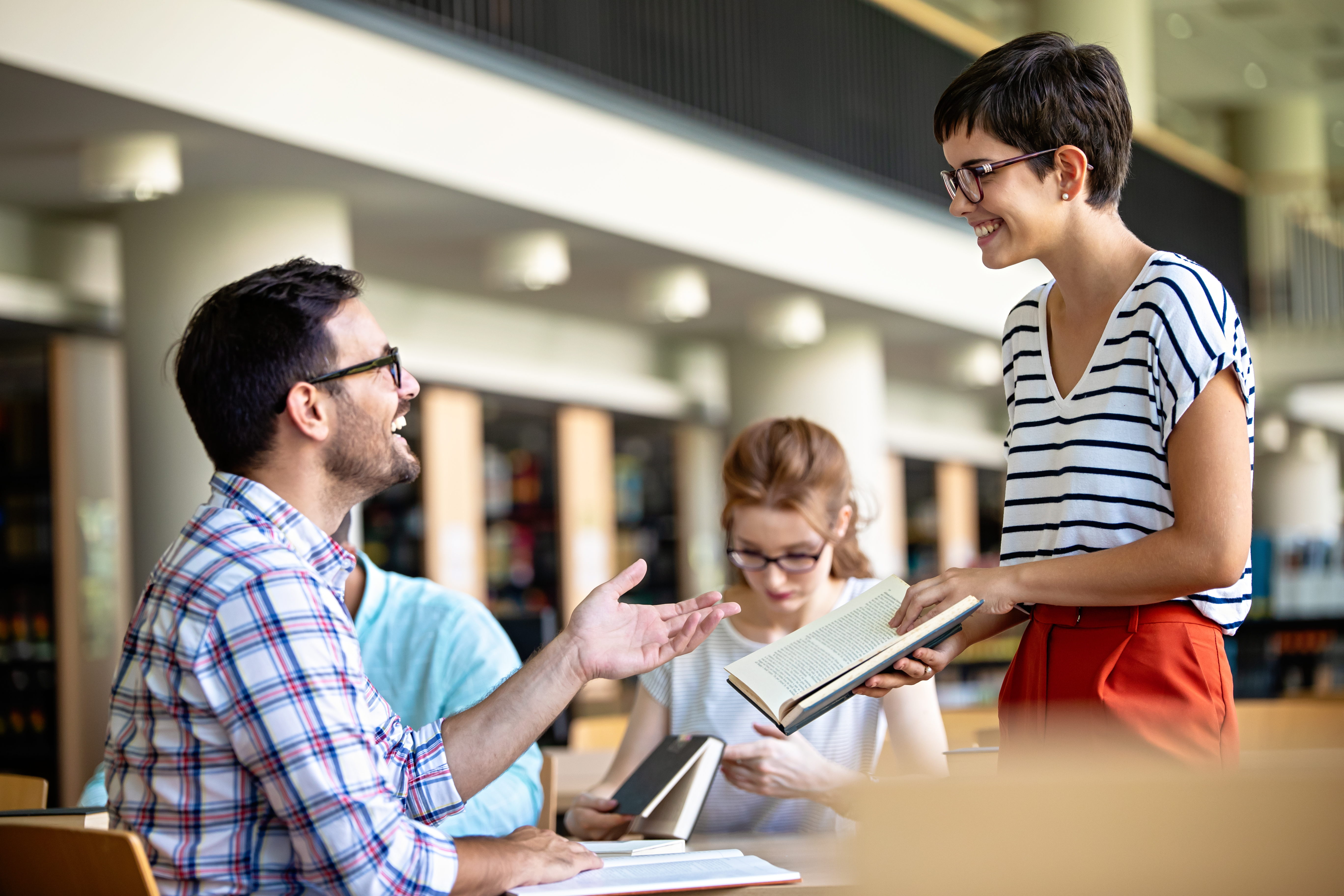 Feliz grupo de estudiantes exitosos que estudian y trabajan juntos en la biblioteca de una universidad