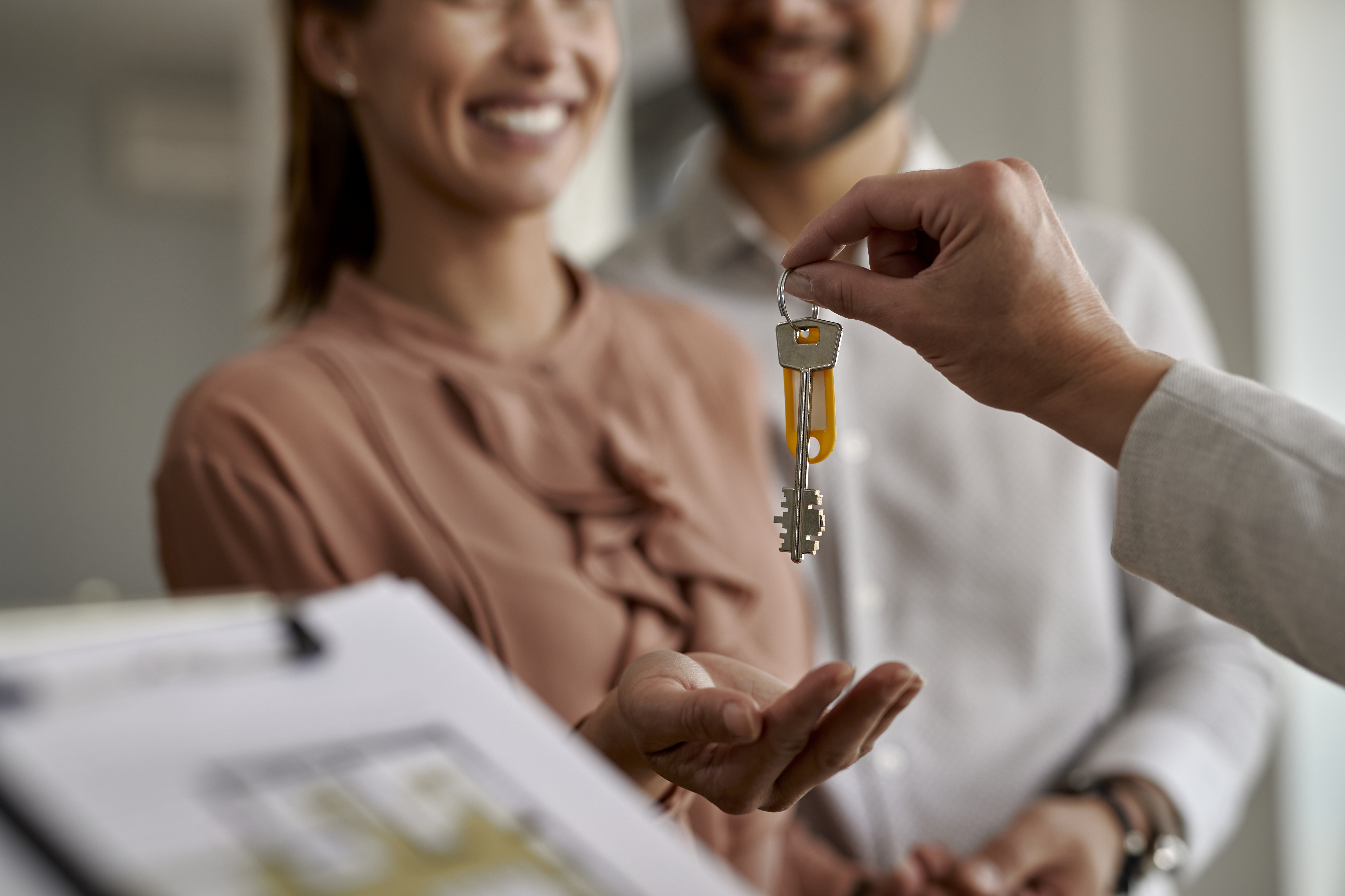 Primer plano de una pareja que recibe las nuevas llaves de la casa de un agente inmobiliario